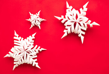 white volumetric christmas snowflakes made of paper on a red background