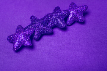 Christmas stars toy on a violet background. Christmas background. Color 2022. 