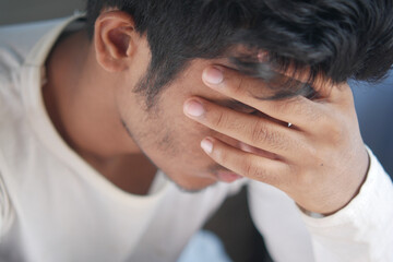 Close up of sad man covering face with hand.