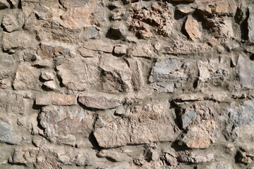 Background, texture of stone. A wall of rough stones with a layer of cement.