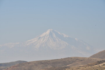 Fototapeta na wymiar Panoramic view of the mountains and the snow-capped peak of Mount Ararat. The top of the mountain in the fog.