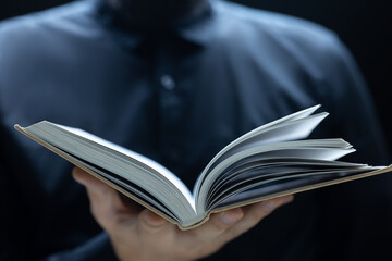 close-up of the open pages of a book that a man holds in front of him