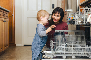 Boy Helping Mother To Load Utensils In Dishwasher