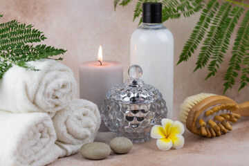 Obraz na płótnie Canvas Spa still life treatment composition on massage table in wellness center. Twisted hot towel with aromatic candles and brush on beige background. Aroma therapy setting.