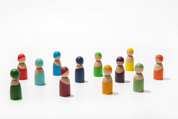 Wooden people of different colors together on endless white background.