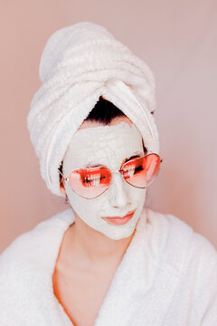 Young woman with beauty face mask wearing heart shape sunglasses