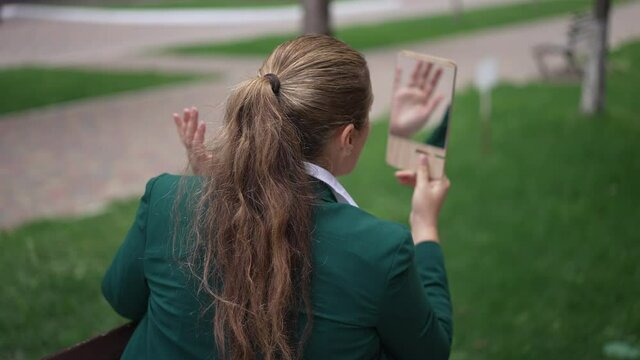 Brunette Caucasian overweight woman admiring reflection in hand mirror sitting on city street outdoors. Back angle view confident adult lady with ponytail adjusting makeup in slow motion