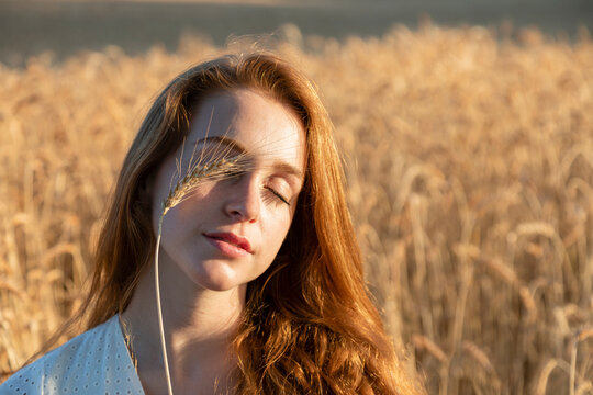 Woman with wheat on closed eyes during sunny day