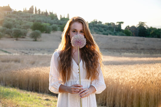 Young woman holding garlic flower on agricultural field
