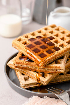 Maple syrup pouring on stack of fresh waffles