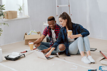 Couple is spending time in new apartment redecorating room paint walls painting accessories...