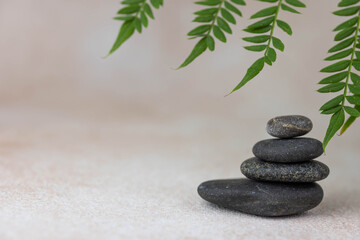 Pyramids of gray zen pebble meditation stones with green leaves on beige background. Concept of...