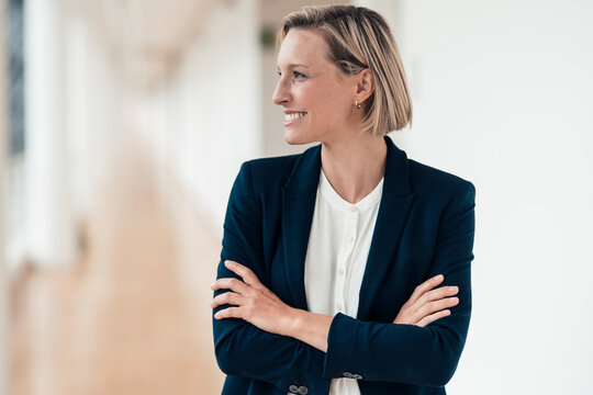 Smiling businesswoman with arms crossed looking away in office