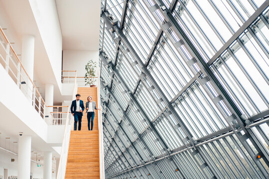 Business partners having discussion while walking on staircase in office