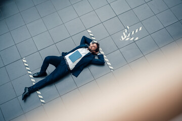 Businessman with digital tablet looking away while lying on office floor
