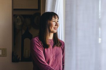 Happy Woman Looking Through Window At Home