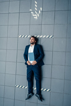 Businessman with digital tablet resting on floor by arrow symbol in office
