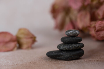 Pyramids of gray zen pebble meditation stones with green leaves on beige background. Concept of...