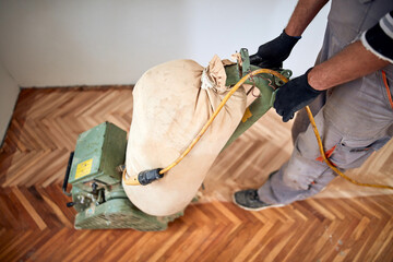 Repairman restoring parquet with a sanding machine.