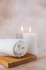 Naklejka na ściany i meble Spa still life treatment composition on massage table in wellness center. Twisted hot towel with aromatic candles on beige background. Aroma therapy setting. Concept of harmony, balance and meditation