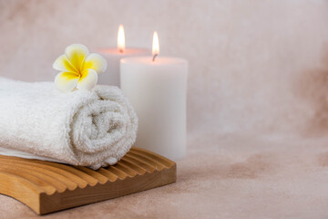 Naklejka na ściany i meble Spa still life treatment composition on massage table in wellness center. Twisted hot towel with aromatic candles on beige background. Aroma therapy setting. Concept of harmony, balance and meditation
