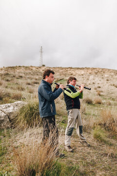 Male friends playing dulzaina while standing in field