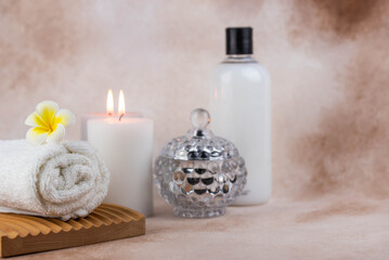 Obraz na płótnie Canvas Spa still life treatment composition on massage table in wellness center. Twisted hot towel with aromatic candles on beige background. Aroma therapy setting. Concept of harmony, balance and meditation