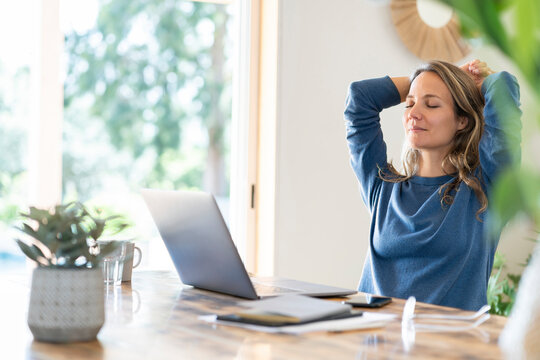 Relaxed female professional sitting with eyes closed while taking break from work at home