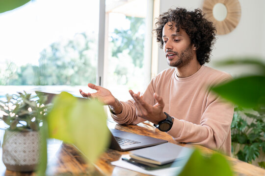 Businessman gesturing during video conference on laptop at home