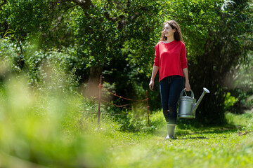 Woman walking in vegetable garden holding watering can