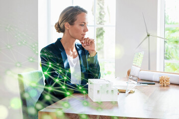 Businesswoman with hand on chin using futuristic digital tablet at office