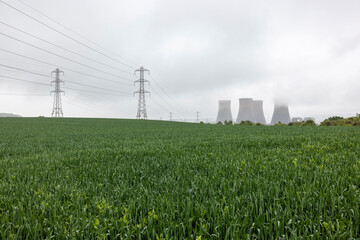 UK, England, Rugeley, Field with electricity pylons and cooling towers in background