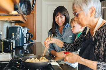 Woman With Son Looking At Mother Cooking Chinese Dumplings