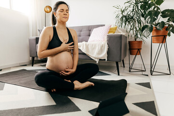 Obraz premium Pregnant woman practicing yoga at home