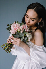 Naklejka premium Young bride with a bouquet of flowers in her hands White dress on her body Morning preparations before the engagement ceremony
