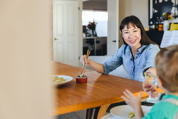 Smiling Woman Eating Dumpling While Feeding Son