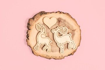 Wooden figurines of deers and heart on pink background, symbol of love. Eco decor, blank for a card for Valentine's day, weddings, engagement