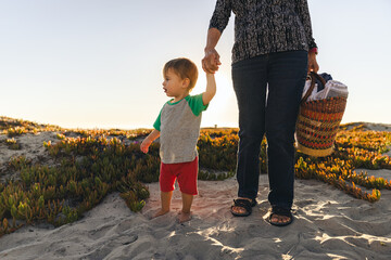Cute Toddler Boy Holding Hand With Grandmother At Beach - Powered by Adobe