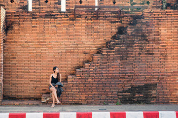 Attractive asian woman sitting on brick wall stairs in Tha Phae Gate at Chiang Mai