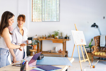 Female creative professionals discussing at desk in art studio