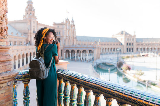 Happy female tourist photographing from balcony, Plaza De Espana, Seville, Spain