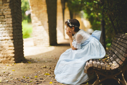 Girl with hand on chin contemplating while sitting on bench