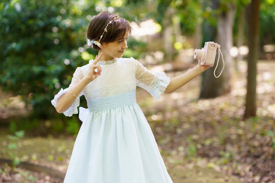 Smiling girl talking selfie through camera on communion day in garden