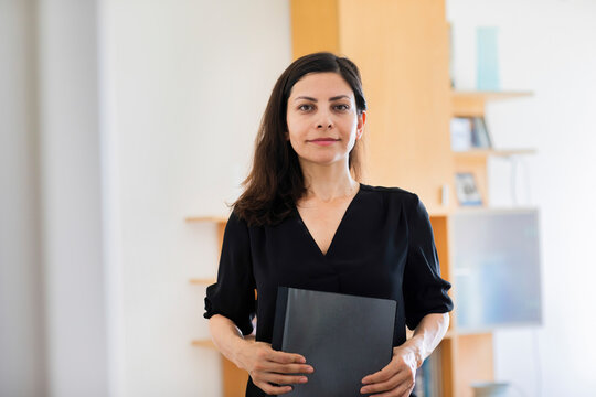 Female professional with file standing in office