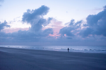 Woman taking cloudy sunrise walk on the beach on Hilton Head Island, South Carolina.