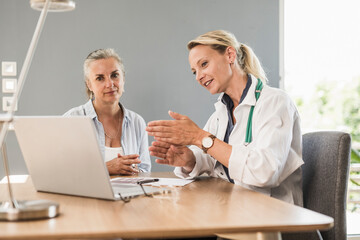 Female doctor gesturing while explaining to patient at office