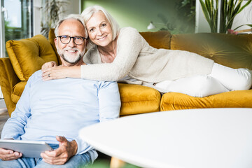 Smiling woman embracing man while resting on sofa at home