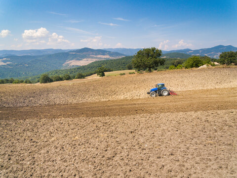 Tractor plowing in farm against sky, Italy