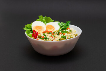 Beautiful Noodle Dish with Green Pea, Carrot, Eggs, Red Hot Pepper and Greens on Black Background. Instant Noodles with Vegetables