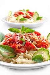 Pasta with tomato sauce basil and grated parmesan on the white plate